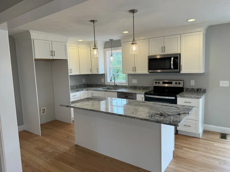 Modern kitchen with white cabinets, granite countertops, and stainless steel appliances.