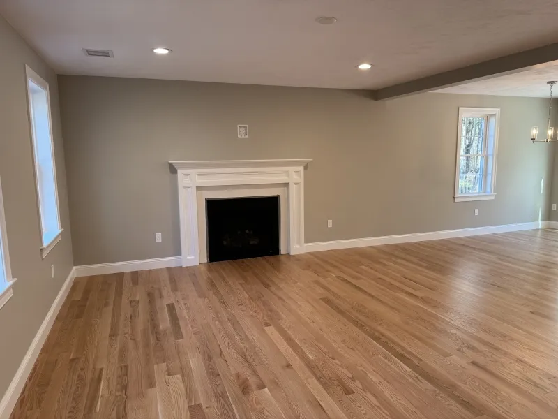 Spacious empty living room with hardwood floors, fireplace, and neutral walls.
