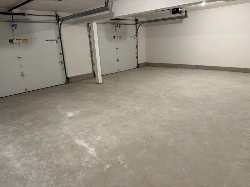 Empty two-car garage with concrete floor and two closed garage doors.