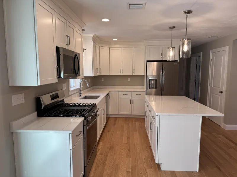Modern kitchen with white cabinets, stainless steel appliances, and a central island.