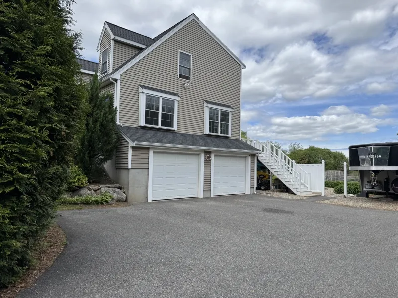 Two-car garage with gray siding, white trim, and an exterior staircase on the right.