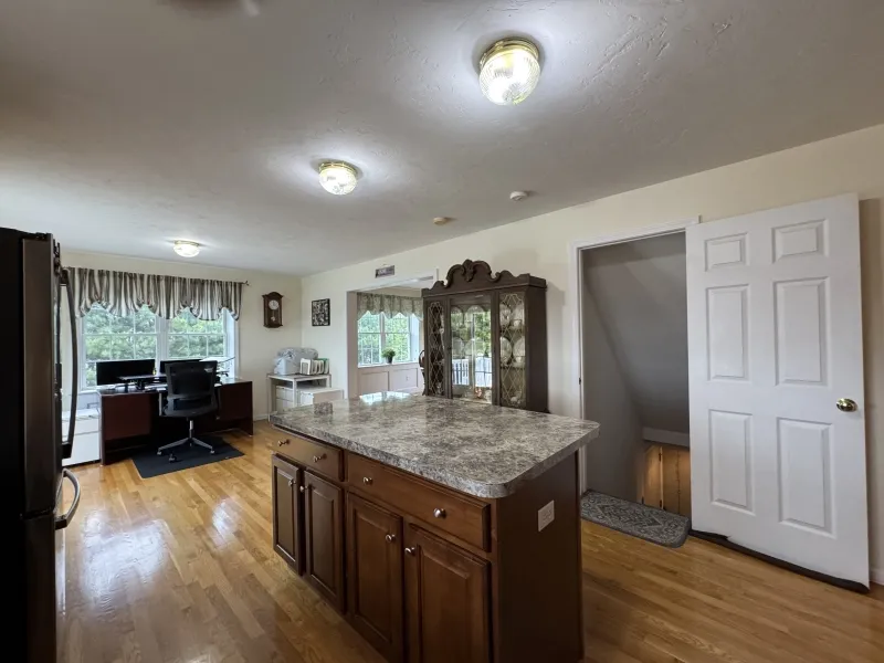 Kitchen with a granite island, hardwood floor, and a home office area by a window.